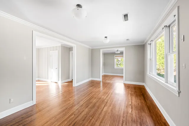 an empty room with wooden floor and windows