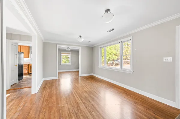 an empty room with wooden floor and windows