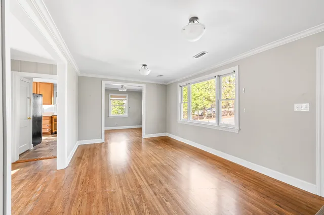 an empty room with wooden floor and windows