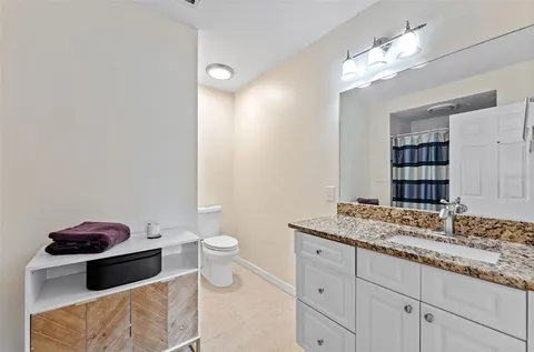 a bathroom with a granite countertop sink a toilet and a mirror