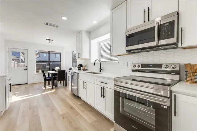 a kitchen with stainless steel appliances a stove microwave and sink