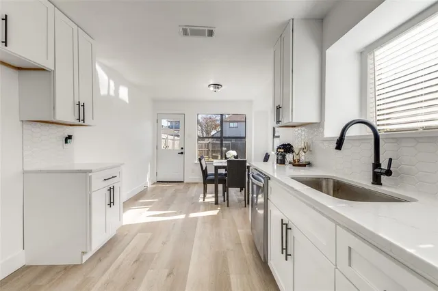 a kitchen with white cabinets and sink