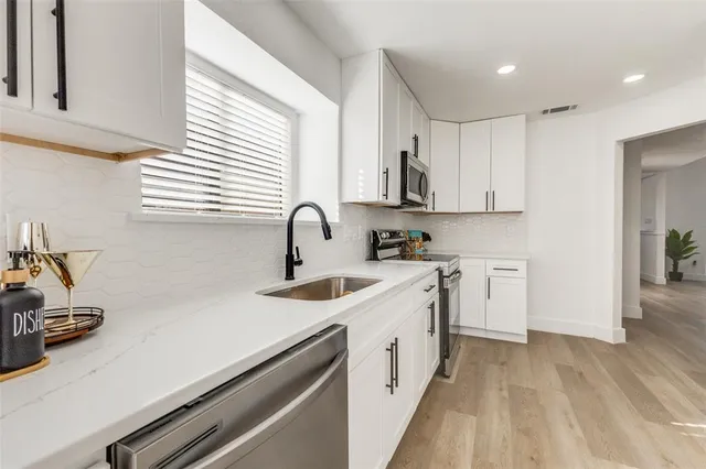 a kitchen with kitchen island a sink appliances cabinets and a counter top space