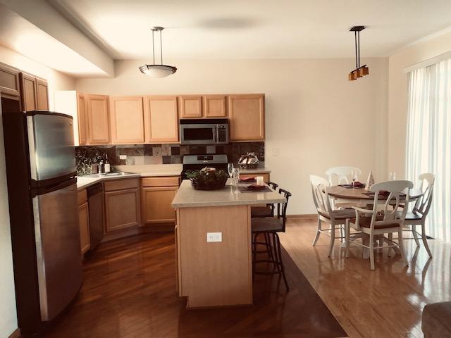 1502 Remington Lane Round Lake, IL 60073 - Photo 6 of 29 a kitchen with stainless steel appliances granite countertop a stove top oven a sink dishwasher a dining table and chairs with wooden floor