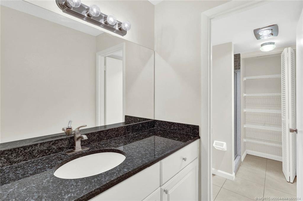 7400 South Ocean Drive, Unit 102 Jensen Beach, FL 34957 - Photo 16 of 26 a bathroom with a granite countertop sink and a mirror