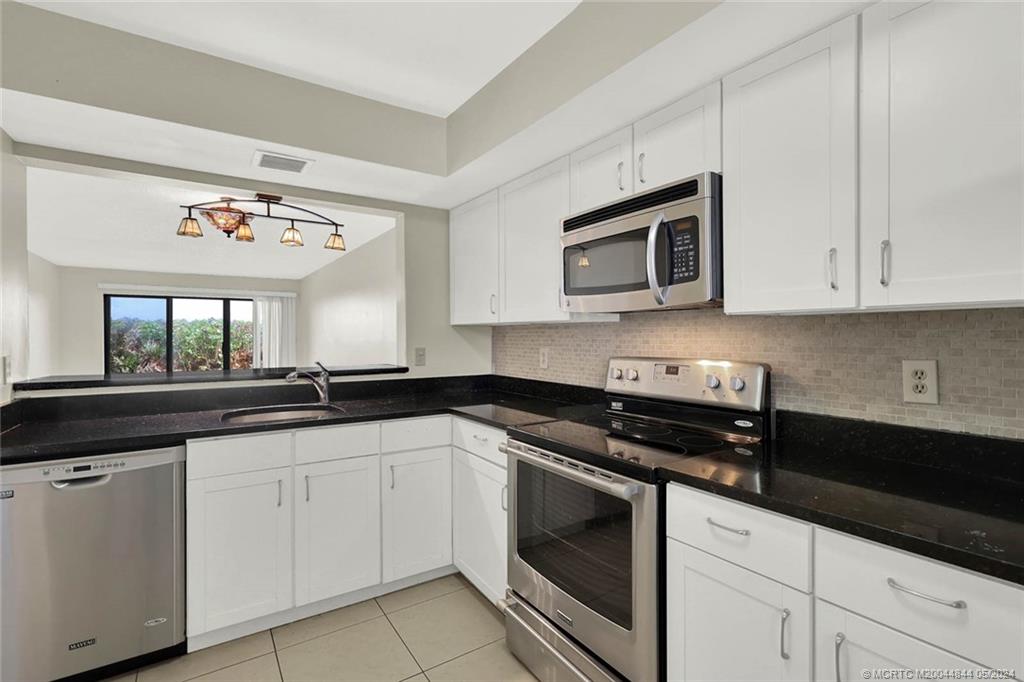 7400 South Ocean Drive, Unit 102 Jensen Beach, FL 34957 - Photo 8 of 26 a kitchen with cabinets appliances and a window