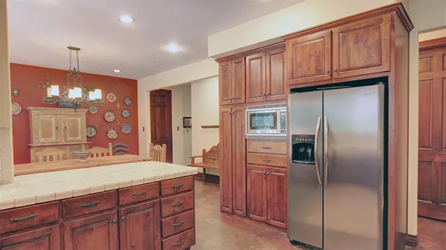 a kitchen with kitchen island granite countertop stainless steel appliances and refrigerator