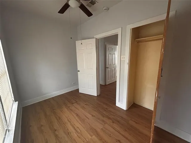 an empty room with wooden floor cabinet and windows