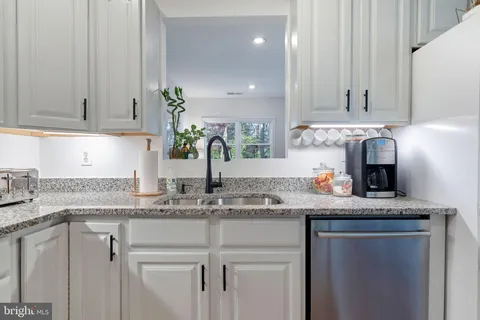 a kitchen with granite countertop a sink stainless steel appliances and white cabinets