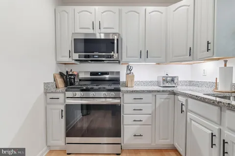 a kitchen with granite countertop white cabinets and stainless steel appliances