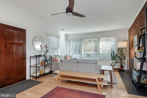 a living room with furniture a rug potted plant and a window