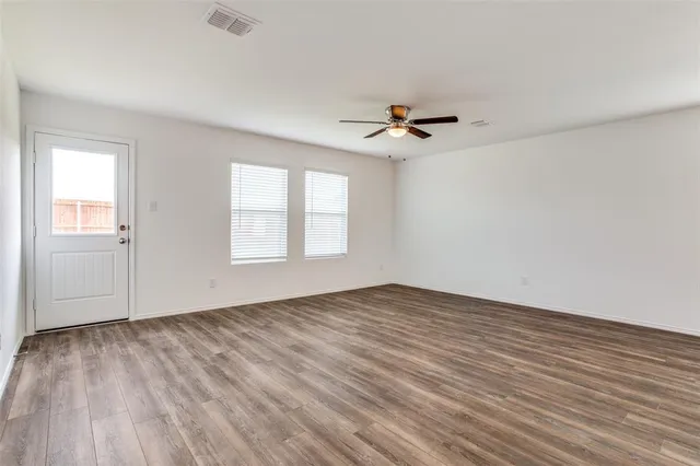 a view of an empty room with a window and wooden floor