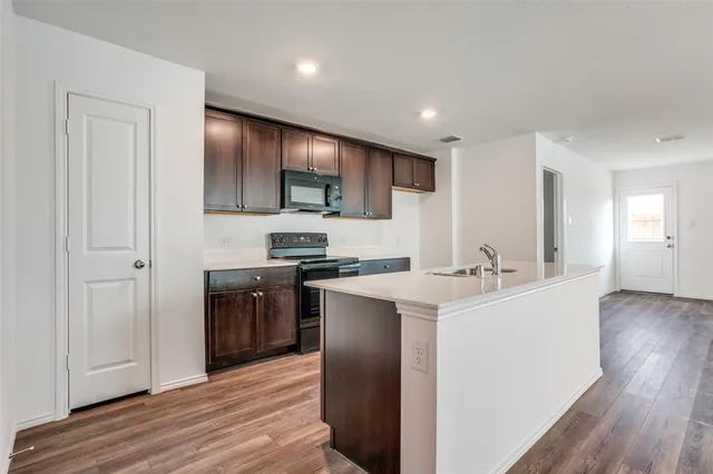 a kitchen with stainless steel appliances a sink stove and wooden floor