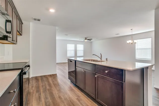 a kitchen with stainless steel appliances granite countertop a refrigerator a sink dishwasher a stove and white countertops with wooden floor