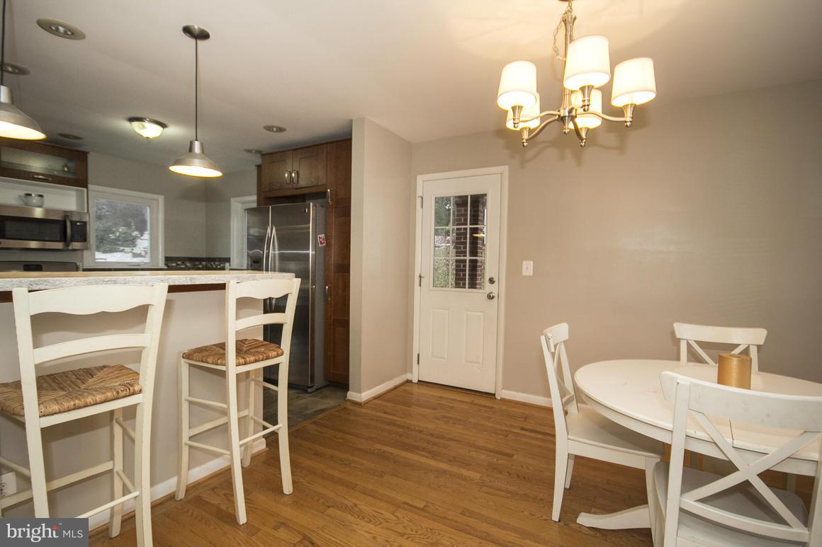 8216 Edwill Avenue Rosedale, MD 21237 - Photo 8 of 27 a dining room with wooden floor a chandelier a wooden table and chairs