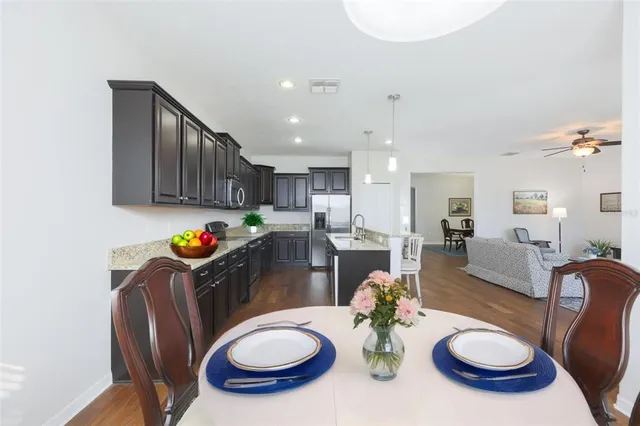 a kitchen with stainless steel appliances granite countertop a sink a stove a dining table and chairs