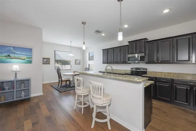 a kitchen with stainless steel appliances granite countertop a table chairs refrigerator sink and cabinets