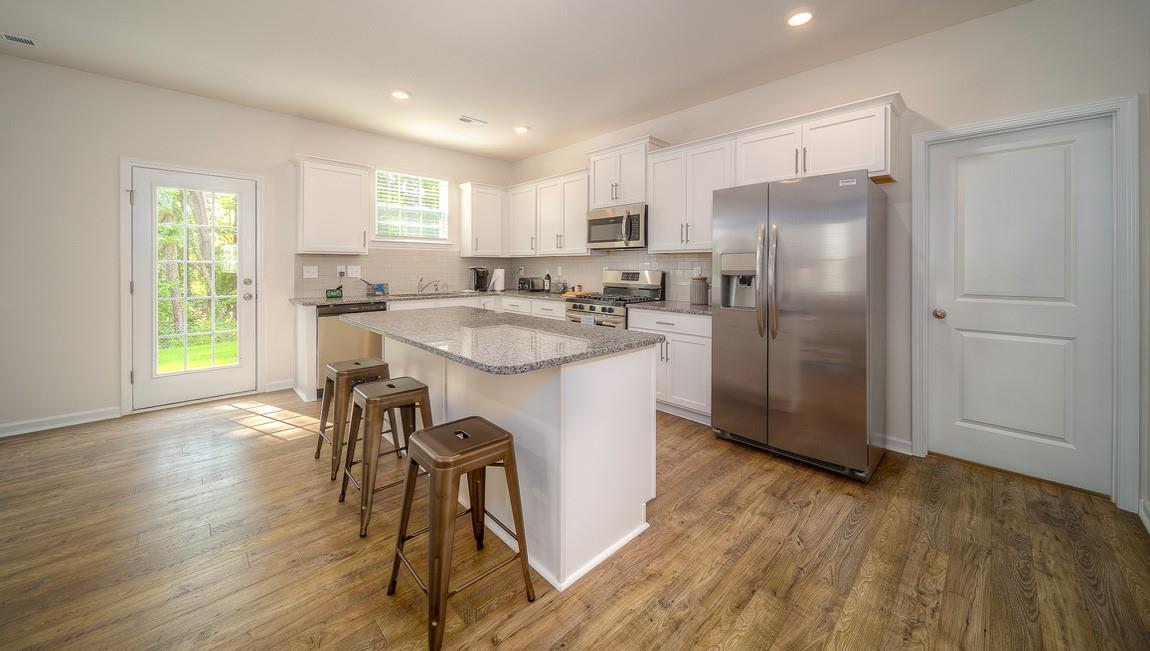 1208 Secrest Cmns Drive Monroe, NC 28112 - Photo 13 of 40 a kitchen with stainless steel appliances granite countertop a refrigerator a stove a sink dishwasher and white cabinets with wooden floor next to windows