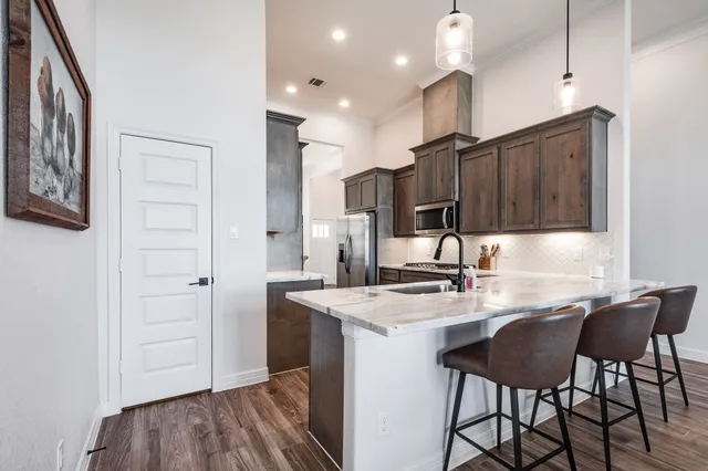 a kitchen with kitchen island a stove a refrigerator and a sink with wooden cabinets