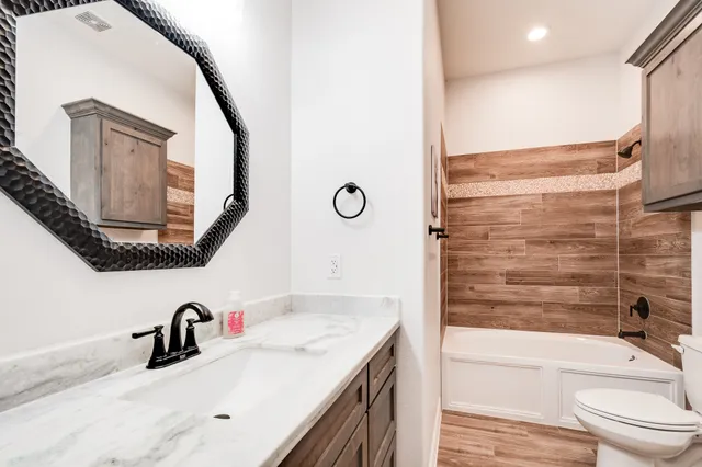 a bathroom with a granite countertop sink mirror and bathtub