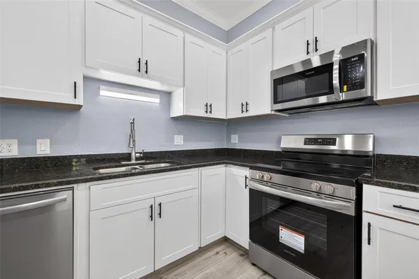 a kitchen with granite countertop white cabinets stainless steel appliances and a sink