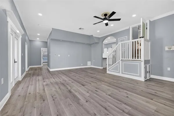 a view of an empty room with wooden floor and a ceiling fan
