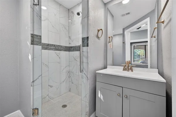 a bathroom with a sink vanity granite tub shower and a mirror