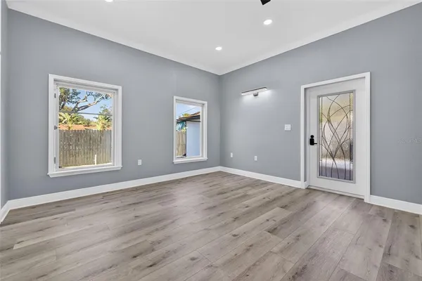 a view of an empty room with wooden floor and a window