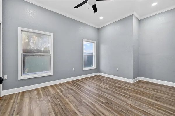 a view of an empty room with wooden floor and a window