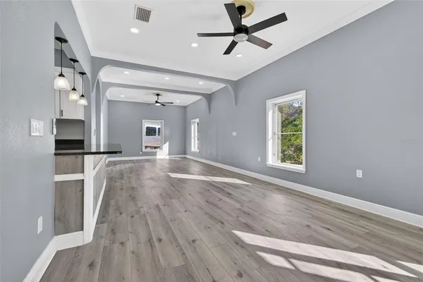 a view of empty room with wooden floor and fan