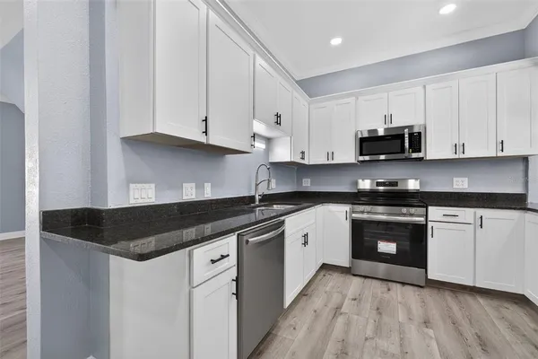 a kitchen with granite countertop white cabinets and black appliances