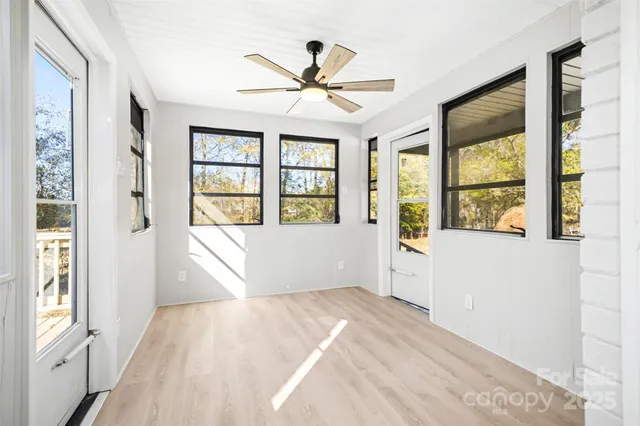 an empty room with windows and fan
