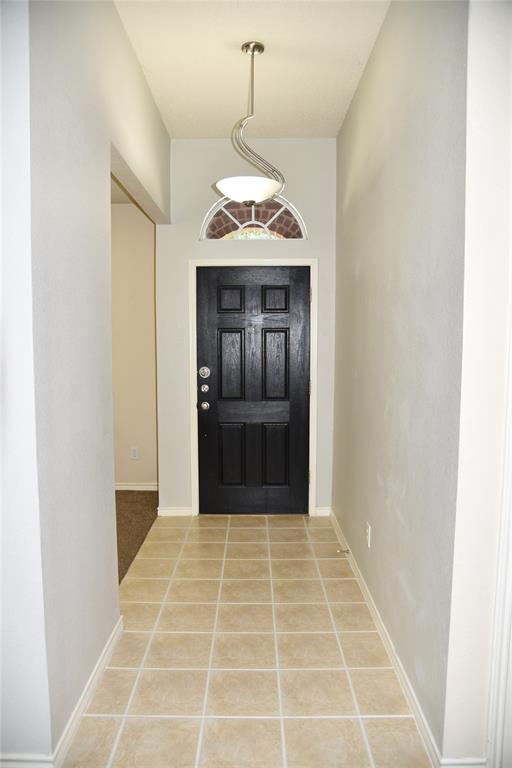 1526 Pebblestone Court Allen, TX 75002 - Photo 2 of 28 Entryway featuring square tan floor tiles, a black panel door, an arched transom window, and a brushed nickel pendant light fixture