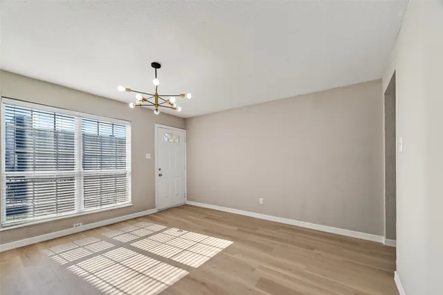 a view of an empty room with kitchen and window