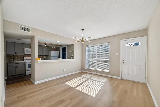 a view of a room with a chandelier fan and wooden floor