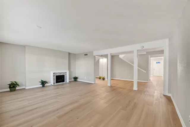 an empty room with wooden floor fireplace and windows