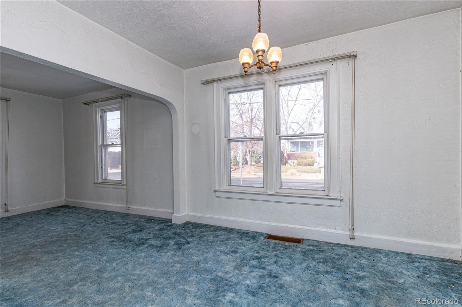 4494 Meade Street Denver, CO 80211 - Photo 5 of 24 an empty room with chandelier fan and wooden floor
