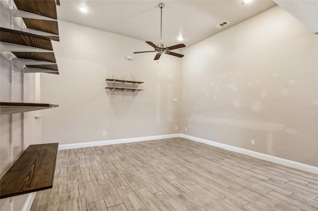 1502 Reed Street Greenville, TX 75401 - Photo 7 of 26 Spacious room featuring vaulted ceilings, wood-finish flooring, a contemporary ceiling fan, recessed lighting, and built-in shelving