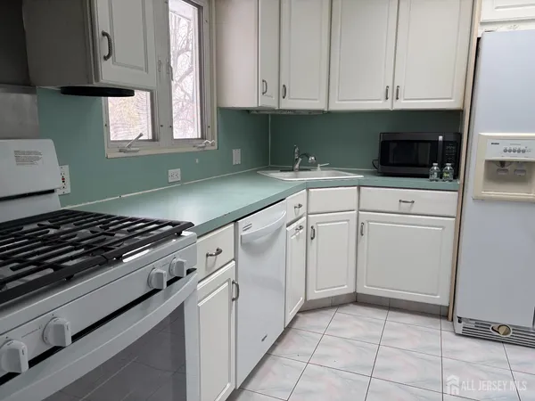 a kitchen with white cabinets and appliances