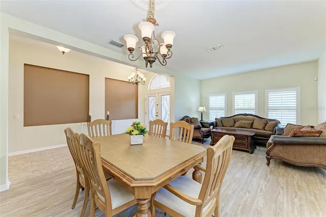 a dining room with furniture a chandelier and wooden floor