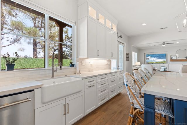 a kitchen with stainless steel appliances kitchen island granite countertop a table chairs in it and white cabinets
