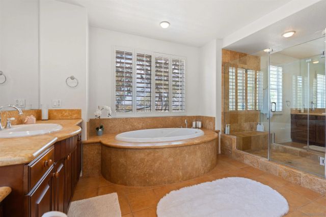 a bathroom with a granite countertop tub a sink and a shower