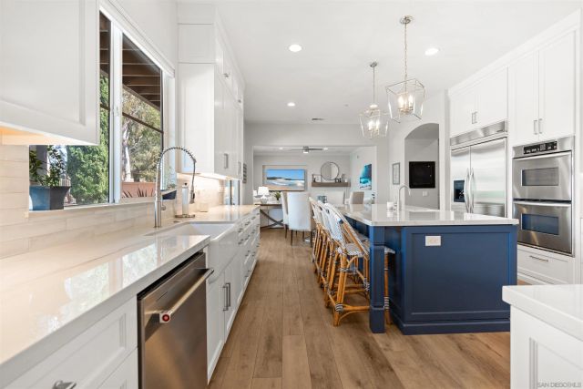 a large kitchen with stainless steel appliances kitchen island granite countertop a large kitchen island a stove a sink a refrigerator and a dining table with wooden floor