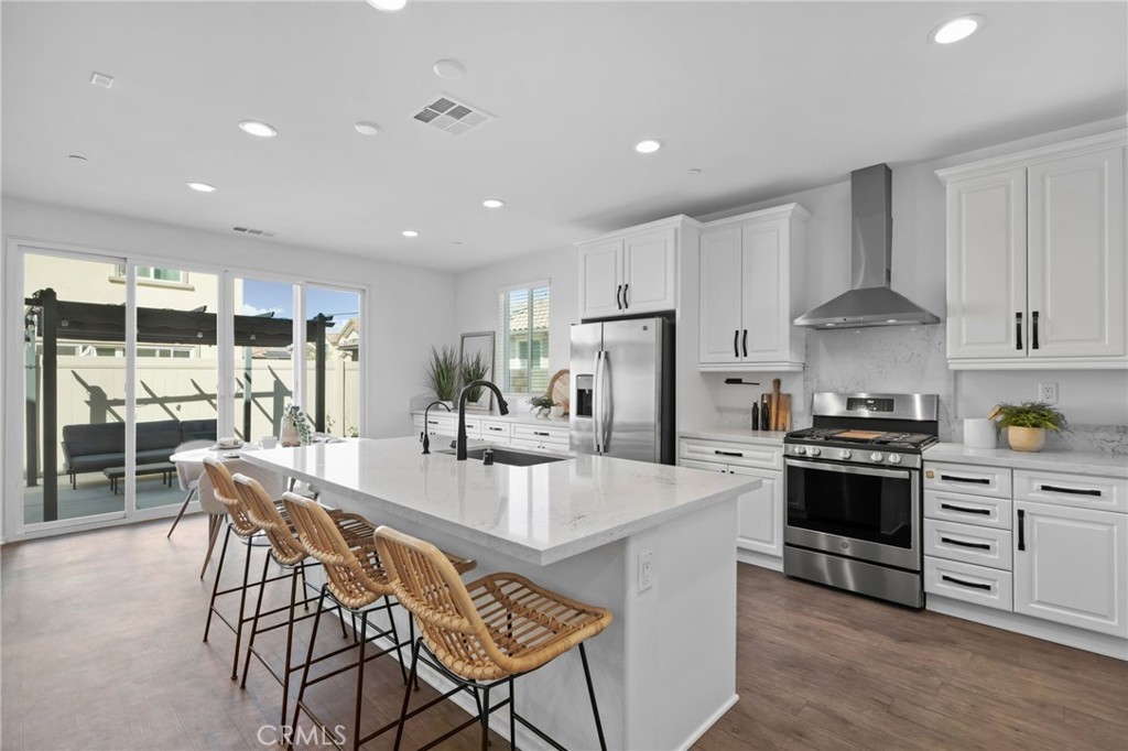 24085 Midvale Court Corona, CA 92883 - Photo 6 of 56 a kitchen with stainless steel appliances a stove a sink a oven a dining table and chairs