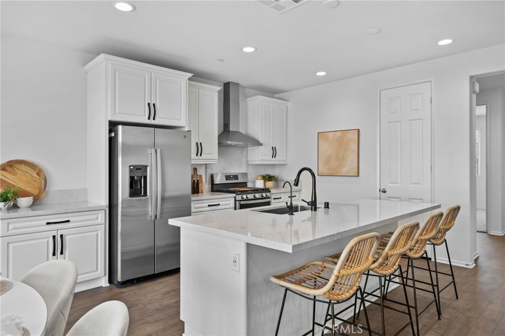 24085 Midvale Court Corona, CA 92883 - Photo 7 of 56 a kitchen with stainless steel appliances granite countertop a stove a refrigerator a white table and chairs
