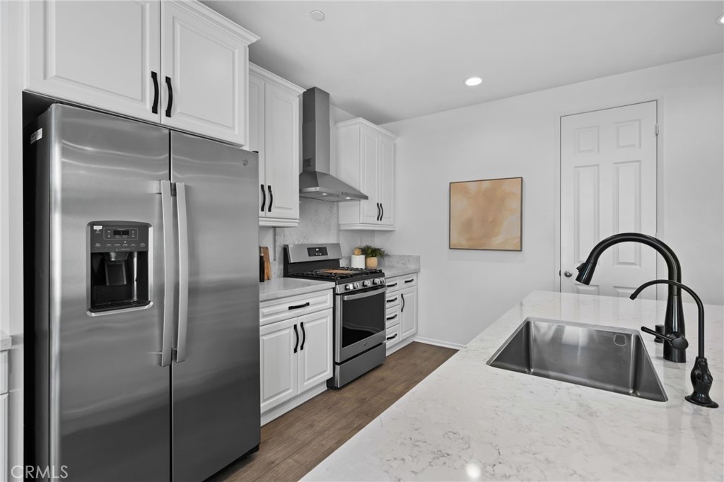 24085 Midvale Court Corona, CA 92883 - Photo 10 of 56 a kitchen with stainless steel appliances granite countertop a refrigerator a sink a stove and white cabinets with wooden floors