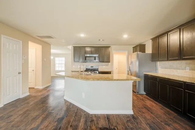 a large kitchen with cabinets wooden floor and stainless steel appliances