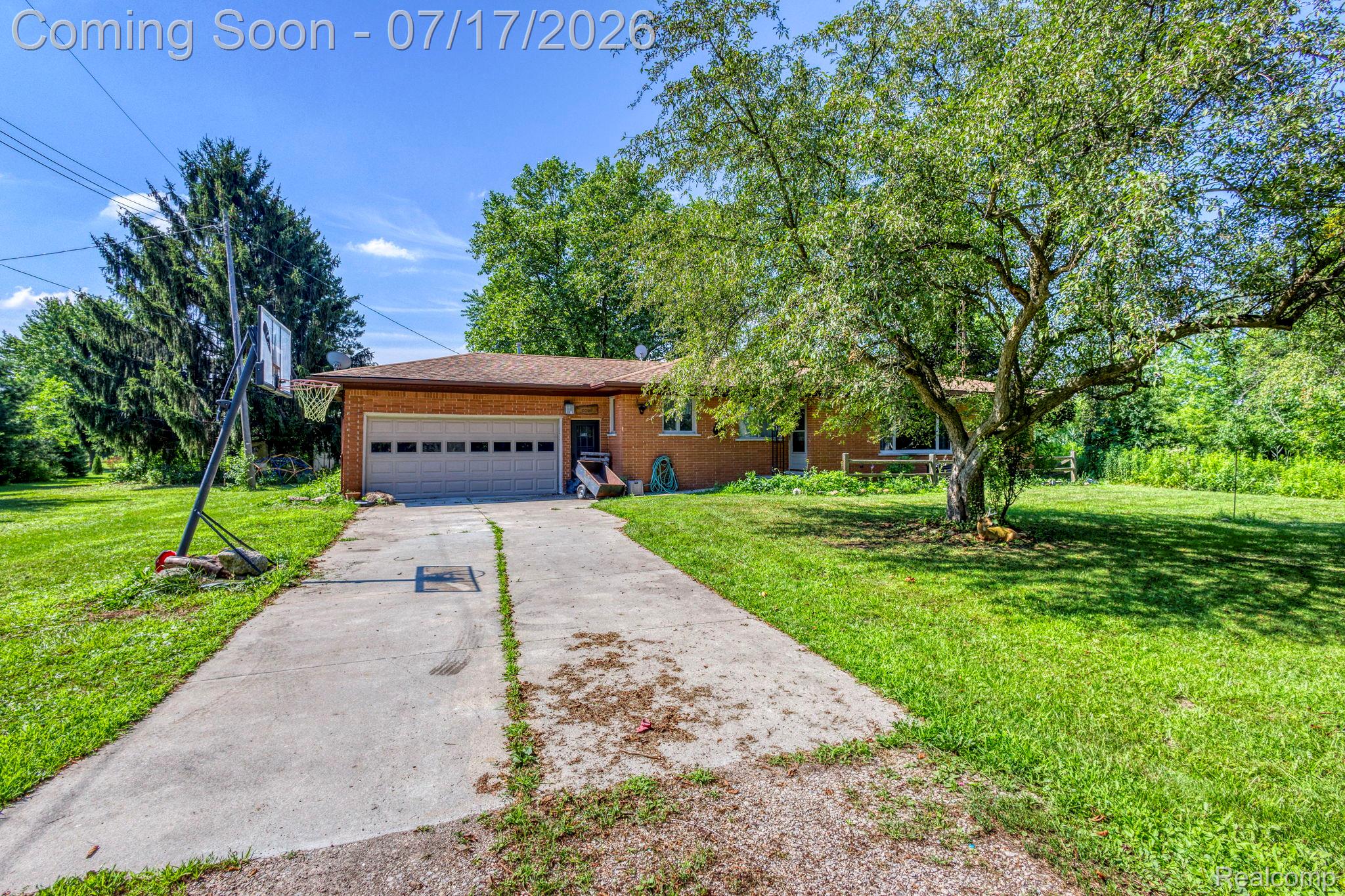 9805 Dolan Road Columbus, MI 48063 - Photo 1 of 39 Brick ranch-style residence featuring a two-car garage, concrete driveway, and expansive front lawn with mature trees