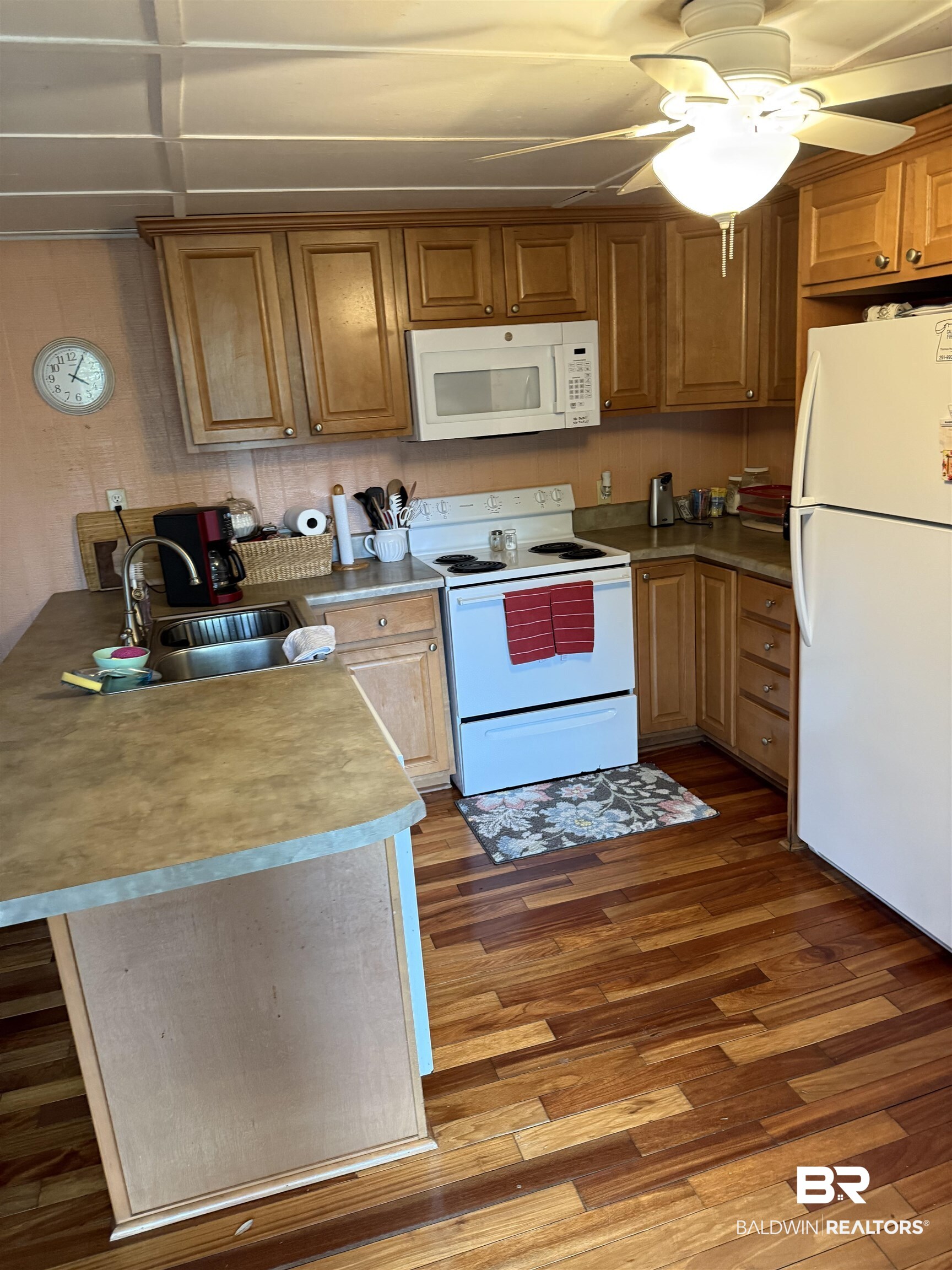 12990 Groves Road Summerdale, AL 36580 - Photo 2 of 8 Kitchen with white appliances, a peninsula, a ceiling fan, a sink, and wood finished floors
