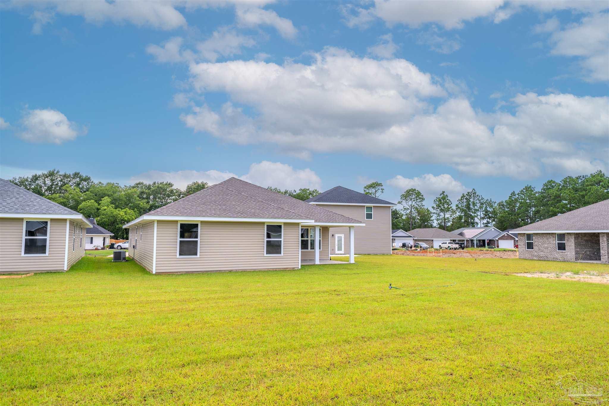 1730 Leigh Loop, Unit 18D Cantonment, FL 32533 - Photo 5 of 18 a white house with a large pool and lawn chairs under an umbrella